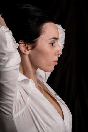 Portrait of beautiful mature brunette woman dressed in white shirt isolated on black backdrop, copy spaceの写真素材