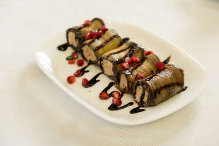 Fried stuffed eggplant with cheese and meat, tomatoes and sauce on white plate, selective focusの写真素材