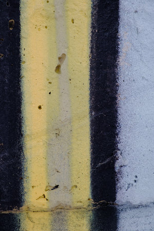 Old black yellow paint with cracks on brick wall as background, texture, selective focusの写真素材