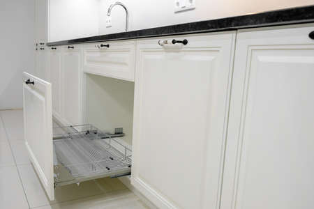 Side view modern and elegant kitchen with white drawers, open kitchen drawer with dish drying rack, selective focusの写真素材