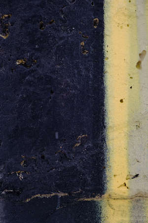 Old black yellow paint with cracks on brick wall as background, texture, selective focusの写真素材