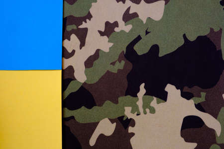 Yellow-blue flag of ukraine on the background of camouflage fabric, background or screensaver, selective focusの写真素材