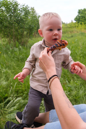 Happy toddler excited about grilled chicken at picnicの写真素材