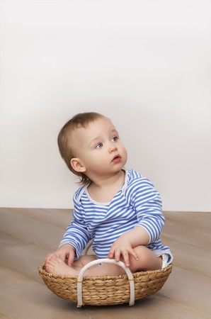 The child is sitting in a pant basket in a striped T-shirt and looks at the cameraの写真素材