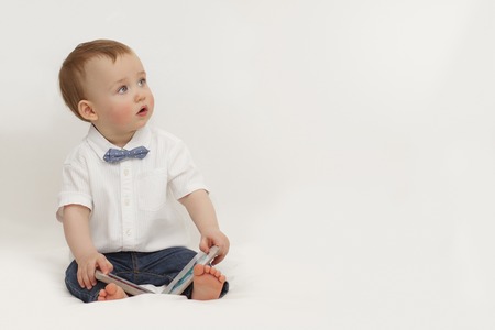 little boy reading a book sitting on a white backgroundの写真素材