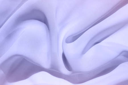 The soft fabric is lined with beautiful deep folds that catch cold light. Abstract art background in trending colors of 2022. The color of Veri Peri.の写真素材