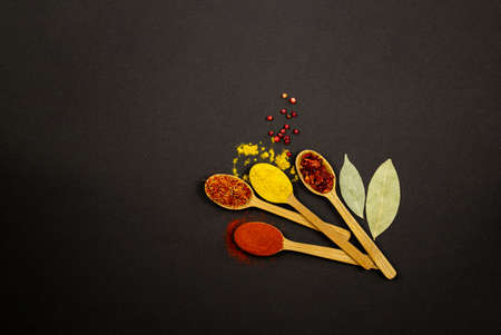 Kit. On a black background, to the right of the center, there are four wooden spoons filled with...