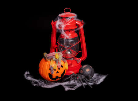 Halloween composition. Red kerosene lamp and a pumpkin with a face on a black backgroundの写真素材