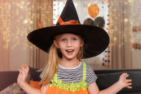 Portrait of a happy little girl dressed as a witch for Halloween, home party