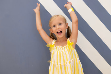 Close up happy little girl in yellow dress on gray background.の写真素材