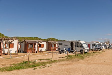 Seaside camping in Spain with wooden cabins, RVs, and trucks. Freedom, travel, and family adventureの写真素材