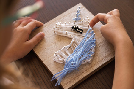 Child creates intricate string art. Fostering focus, creativity, patience, and therapeutic skill developmentの写真素材