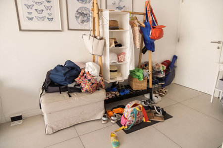 Messy hallway with scattered clothes, shoes, and outerwear, highlighting the need for organizationの写真素材