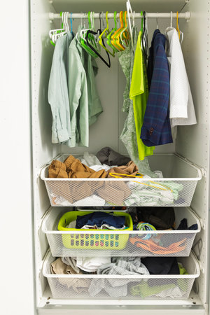 Boy closet with hanging clothes and mesh baskets for tidy storage in an organized children's roomの写真素材