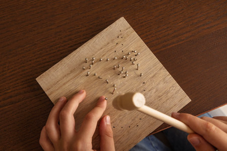 Child hands working on a wooden craft project. Using a hammer, learning skills, and exploring creativityの写真素材