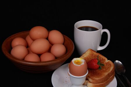 Soft boiled egg coffee and strawberry on black backgroundの写真素材