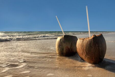 Coconut drinks for two on a sandy beachの写真素材