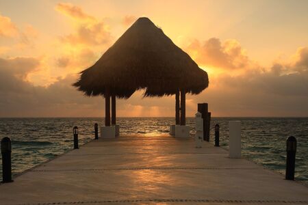 Pier with thatched hut view at sunrise の写真素材