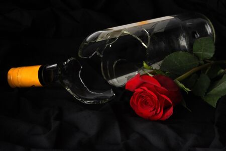 Broken wine bottle layng beside a roseの写真素材