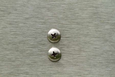 Two screws set into industrial stainless steel