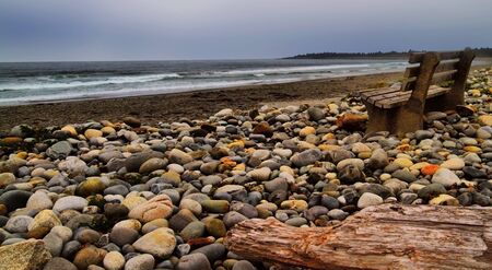 Ocean side on beach with stones and resting benchの写真素材