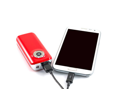 Recharging smart phone tablet from power bank, electricity's source portable on withe background.の写真素材