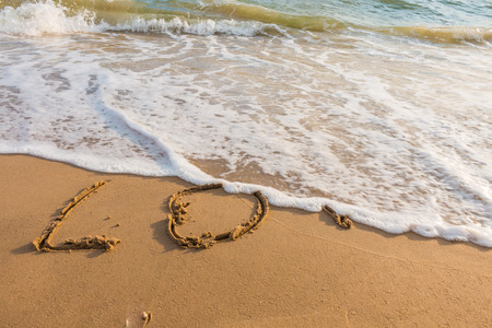 alphabet letters love handwritten in sand on beach for backgroundの写真素材