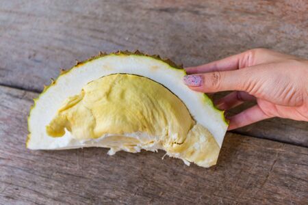 Close up Durian on woman hands on the wood table for backgroundの写真素材