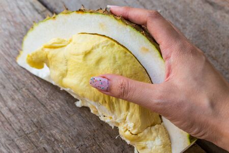 Close up Durian on woman hands on the wood table for backgroundの写真素材