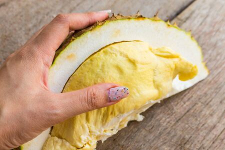 Close up Durian on woman hands on the wood table for backgroundの写真素材