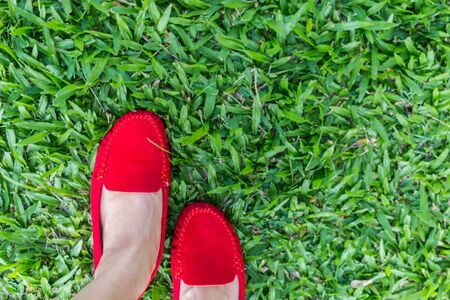 Woman wearing red shoes on the green grass for backgroundの写真素材