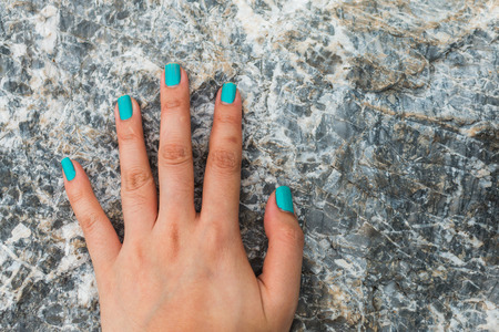 Five fingers is blue nail on stone backgroundの写真素材