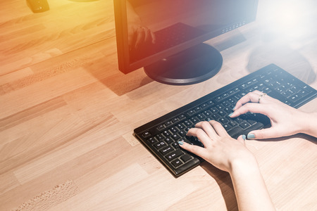 A woman is working by using  computer on table. Hands typing on a keyboard.