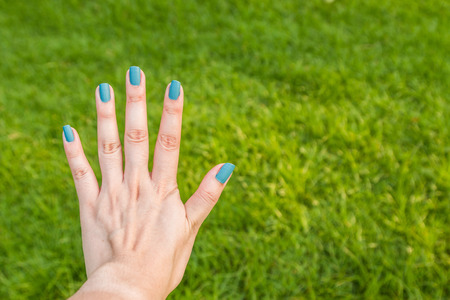 Five fingers is blue nail on green backgroundの写真素材