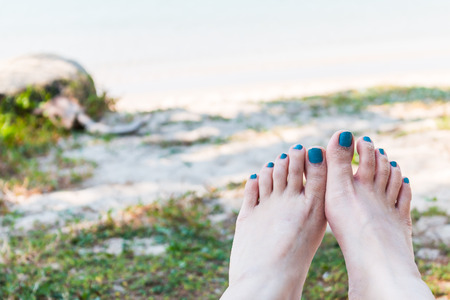 Feet of a young woman lying on the beach view a seaの写真素材