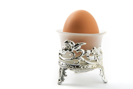 An egg in a transparent glass cup on white backgroundの写真素材
