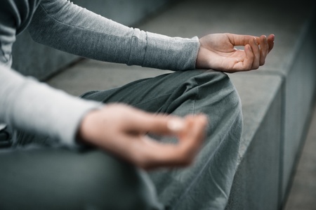 Hands close environment of young woman sitting and meditating yoga meditation 20-25 in modern, cool, outdoorの写真素材