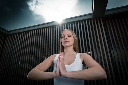 Young woman 20-25 standing and meditating environment yoga meditation in a modern, warm, outdoorの写真素材