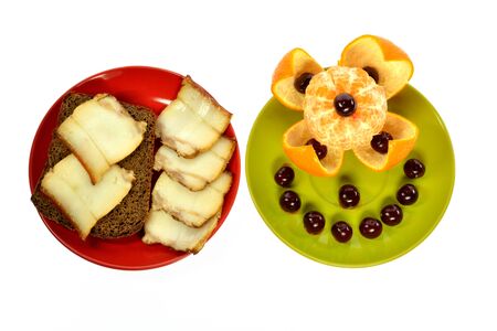 two plates sandwich bread with lard and tangerine with cherries on a white backgroundの写真素材