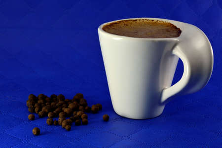Cup of coffee with milk and spice seeds grains on a blue backgroundの写真素材