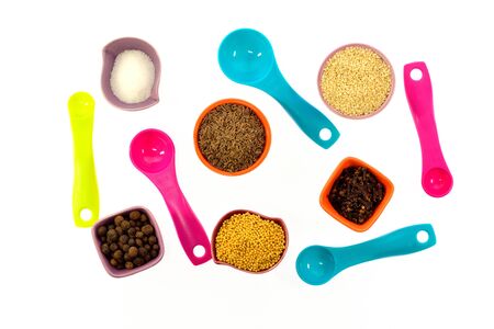 Seeds, spices, grains in small multi-colored cups and measuring spoons on a white backgroundの写真素材