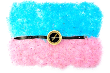 sea shells and a compass with a black strap on blue and pink saltの写真素材