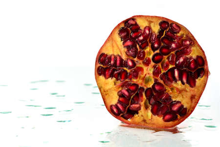 Sliced half of a ripe pomegranate and water drops on glassの写真素材