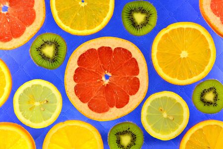 The blue background of the different types of citrus orange, lemon, grapefruit and kiwiの写真素材