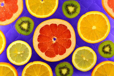 lilac background of the different types of citrus orange, lemon, grapefruit and kiwiの写真素材