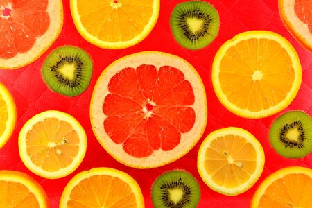 The red background of the different types of citrus orange, lemon, grapefruit and kiwiの写真素材