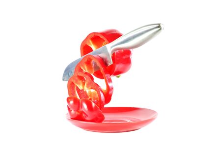 Steel knife cuts red pepper on a white backgroundの写真素材