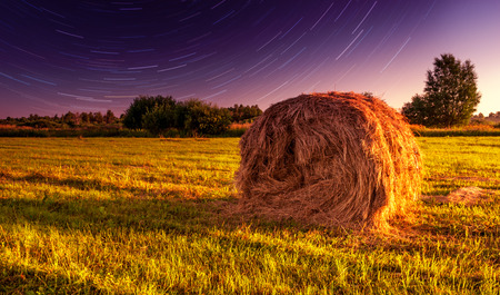 Haystack in the field and the motion of the stars in the skyの写真素材
