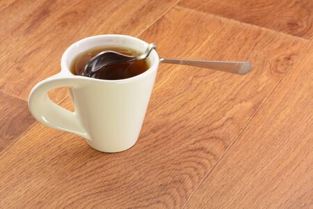 Black tea in a white cup and spoon on wooden backgroundの写真素材