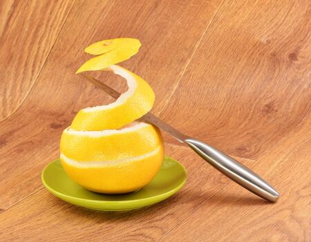 Ripe yellow grapefruit and a knife on a wooden backgroundの写真素材